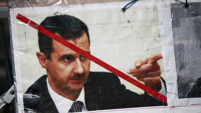 Mit einem roten Strich übermaltes Plakat, das Baschar al-Assad zeigt