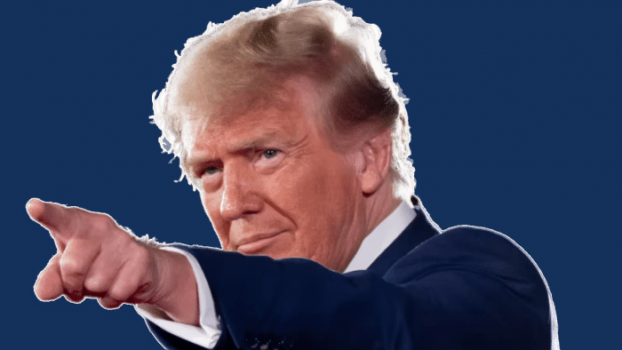 Donald Trump points with an outstretched finger to something outside the left frame of the picture