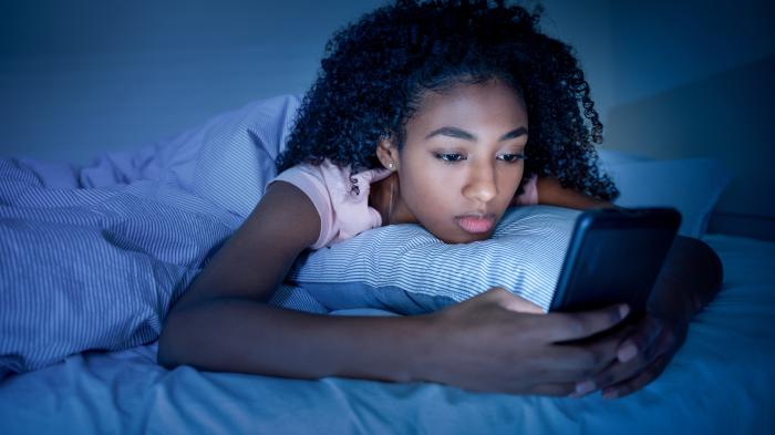 Mädchen mit Smartphone im Bett vor dem Schlafen