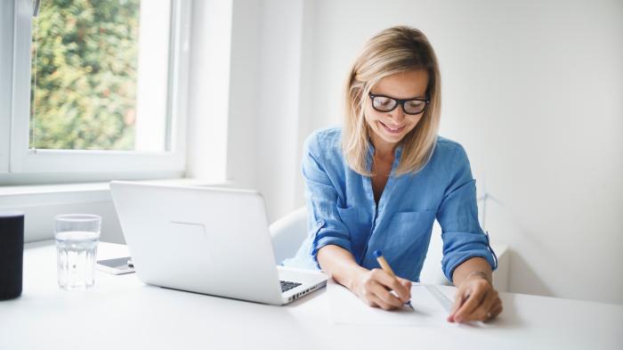 Frau am Arbeitsplatz, schräg vor ihr ein Laptop