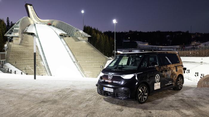 A black VW ID Buzz is parked in front of a snow-covered ski jump in Oslo.