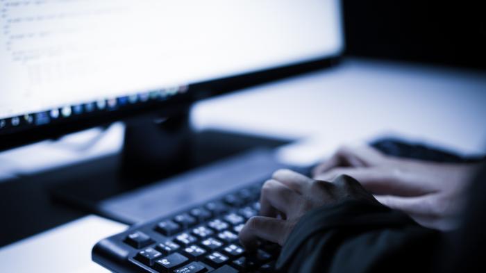 Hand auf Computertatastatur in dunklem Zimmer