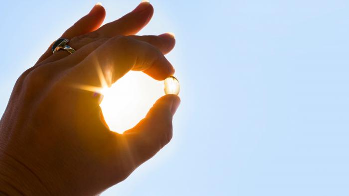 Hand hält eine weiche Kapsel in die Sonne