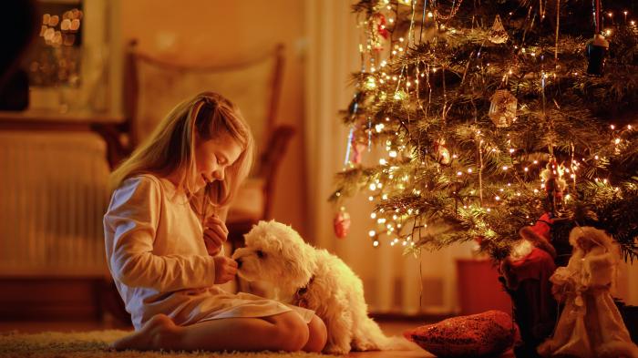Kleines Mädchen sitzt am Weihnachtsbaum
