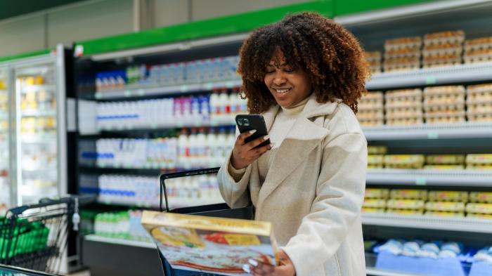 Frau richtet Smartphonekamera auf Pizzaverpackung