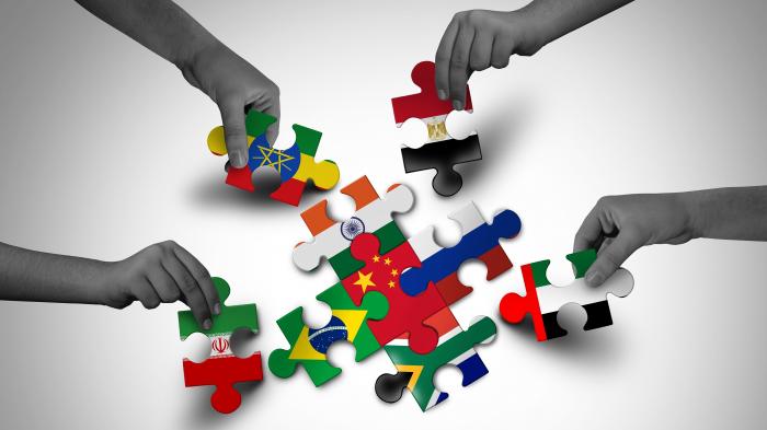 Händer puzzeln Steine, die mit den Brics-Fahnen bedruckt sind