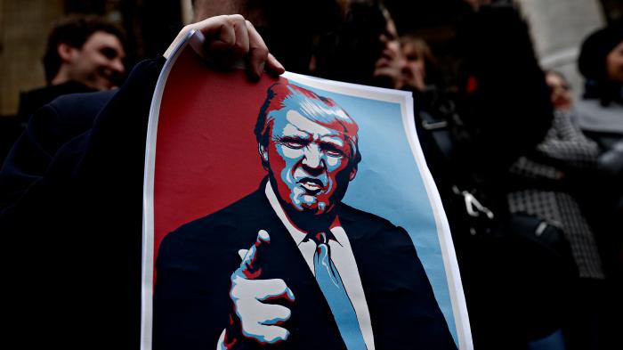 Demonstrant hält Plakat von arrogantem Donald Trump