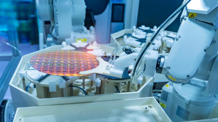 Blau ausgeleuchteter reinraum, in dem ein Siliziumwafer verarbeitet wird.