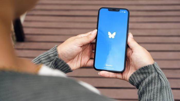 Person holding a mobile phone with the Bluesky logo