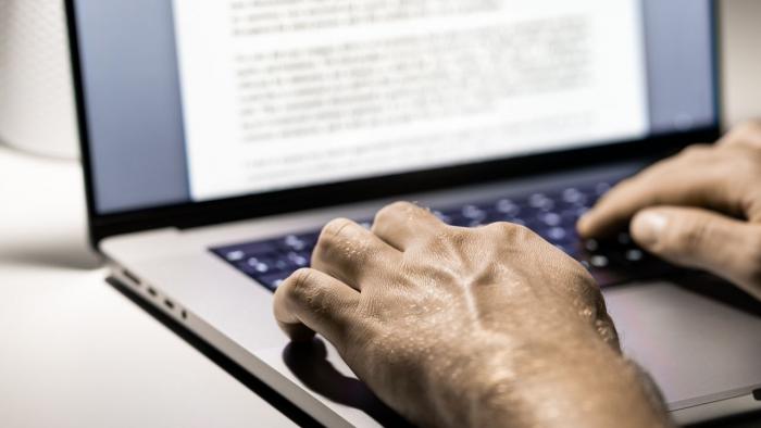 Hand an einer Tastatur und ein Bildschirm