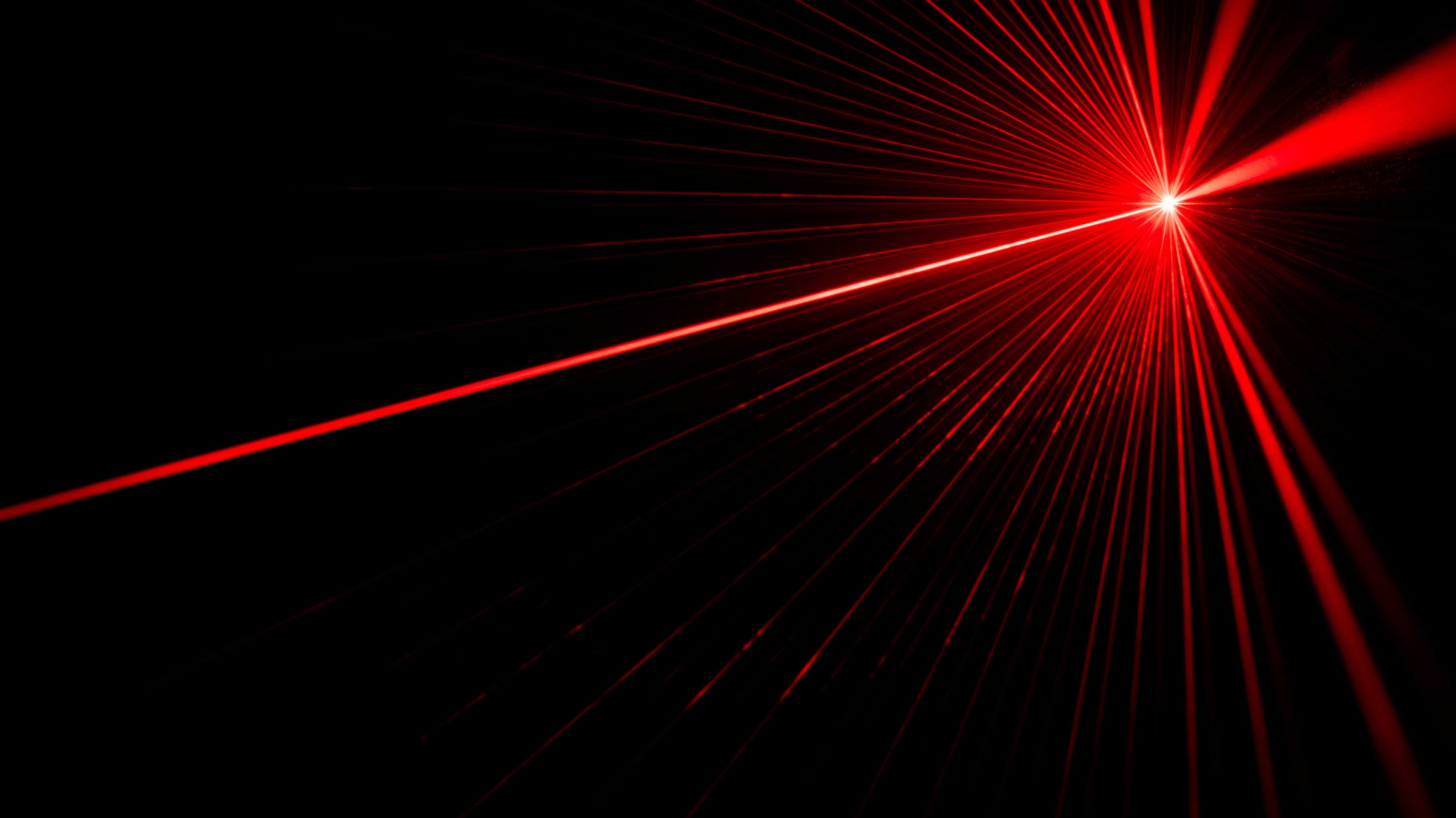 Roter Laserstrahl vor schwarzem Hintergrund.