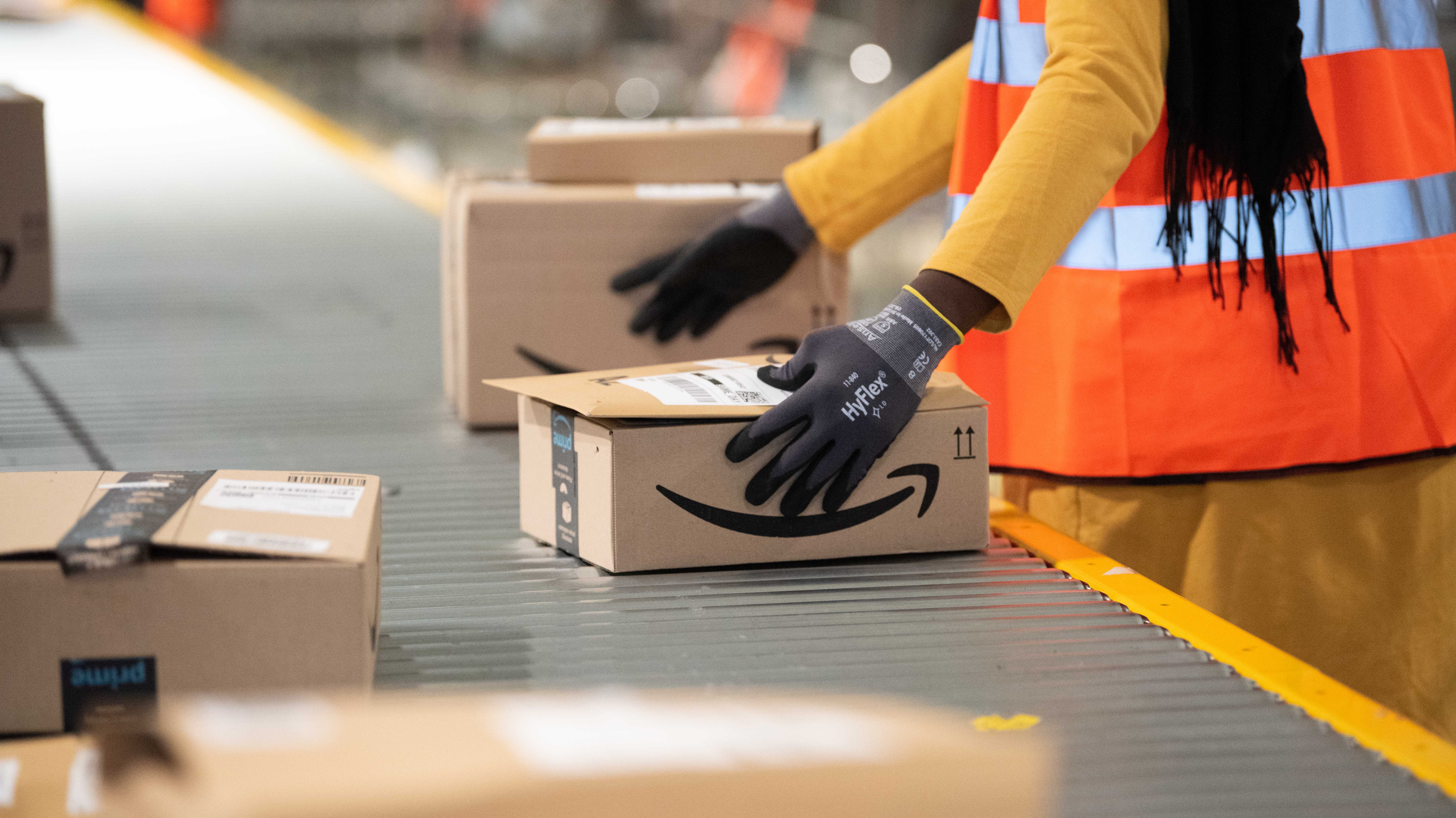 Arbeiter bei Amazon steht mit paketen am Fließband