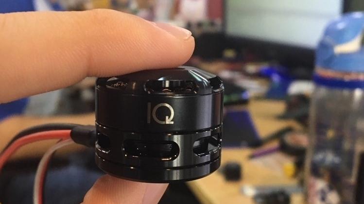 Eine Hand hält einen kleinen schwarzen Motor zwischen Zeigefinger und Daumen