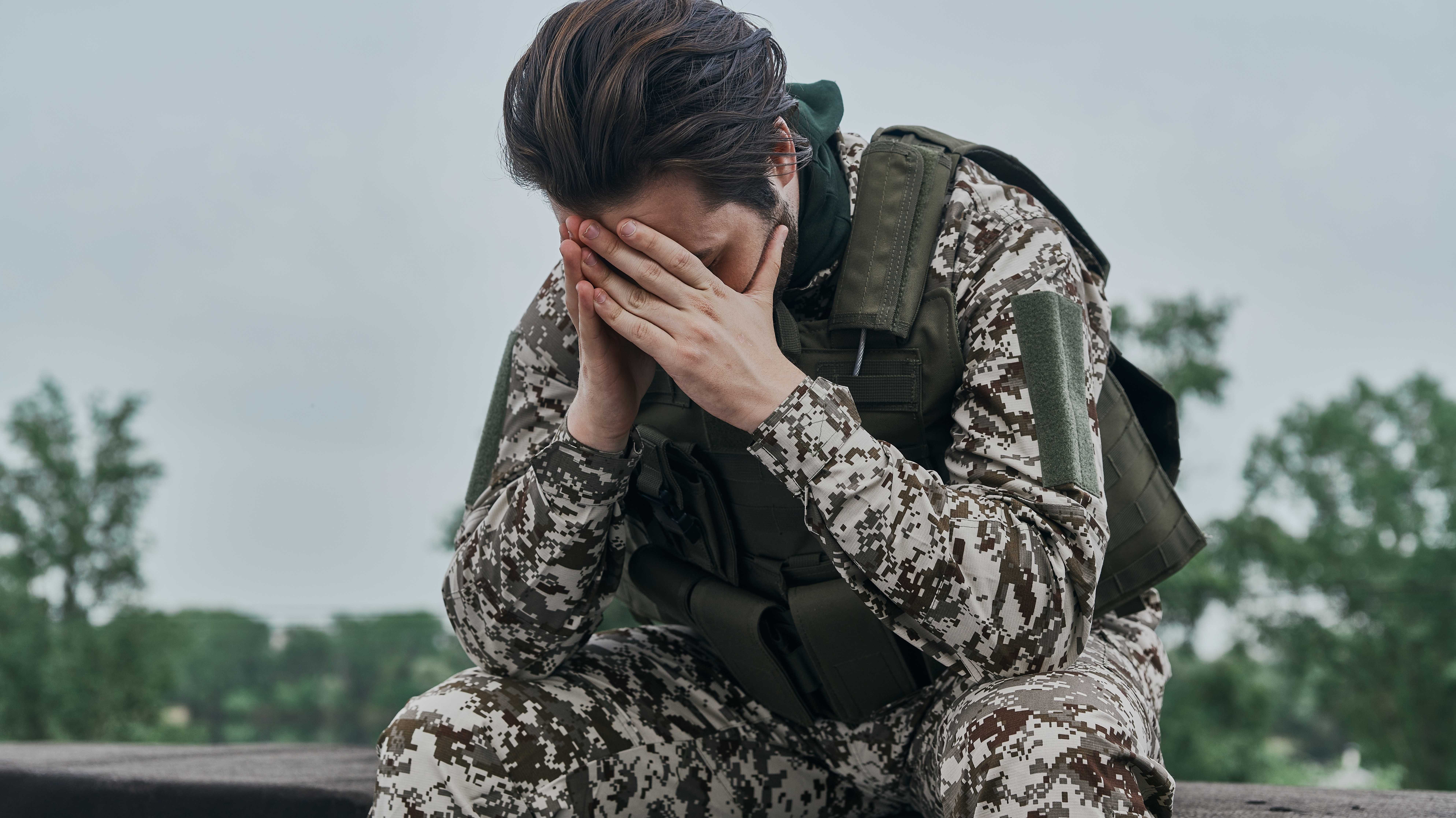 Erschöpfter Soldat, die Hände vor dem Gesicht