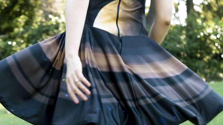 Eine Person trägt ein Kleid, dessen Rock durch die Luft schwingt, darauf leuchten LEDs.